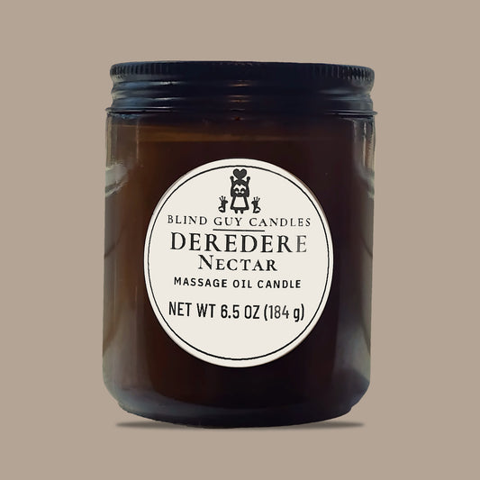 Deredere Nectar massage oil candle, amber glass jar with black lid, on a plain light background